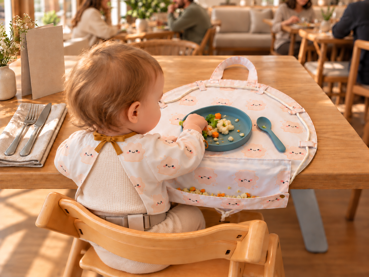 Kind im Hochstuhl isst von der KLECKSI TO GO Unterlage im Restaurant