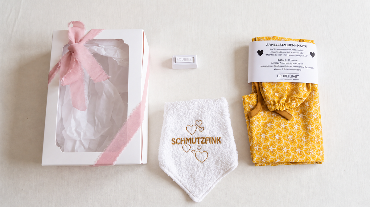 Geschenkbox, Waschtuch SCHMUTZFINK und gelbes HAPSI nebeneinander