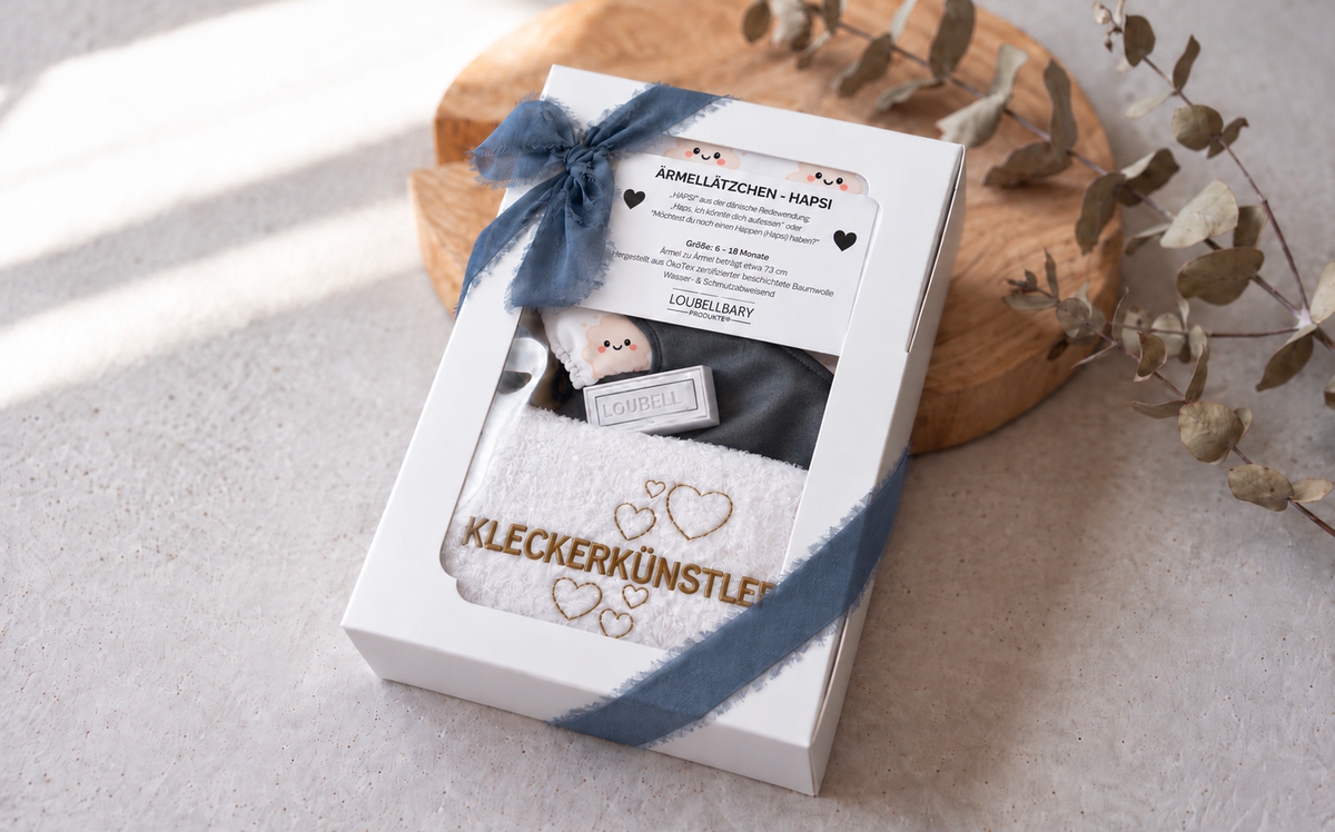 Geschenkbox mit blauer Schleife und besticktem Waschtuch KLECKERKÜNSTLER