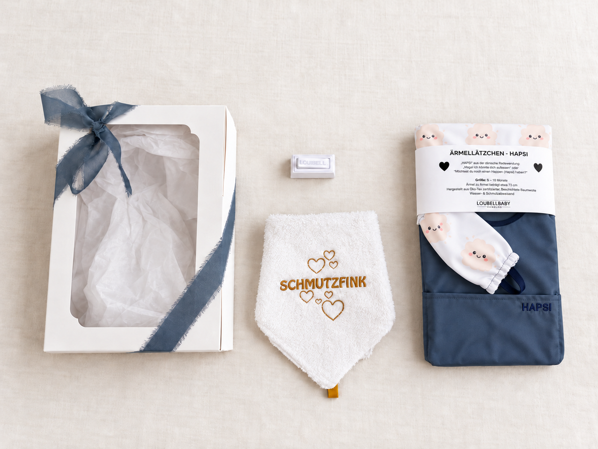 Geschenkbox, Waschtuch SCHMUTZFINK und blaues HAPSI Klecksi nebeneinander
