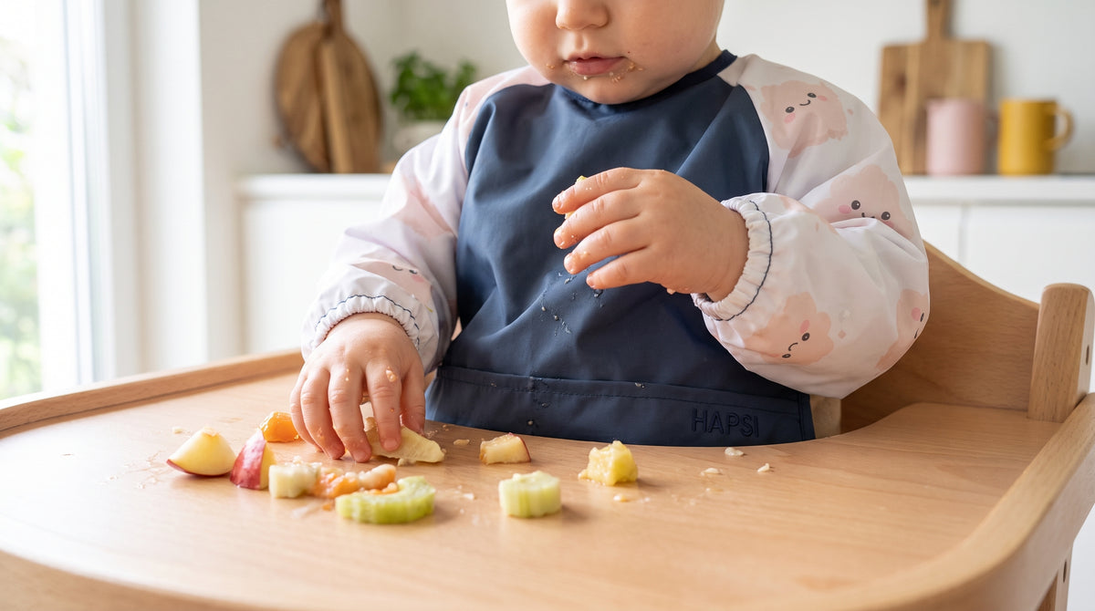 Kleinkind mit blauem HAPSI Klecksi isst Fingerfood