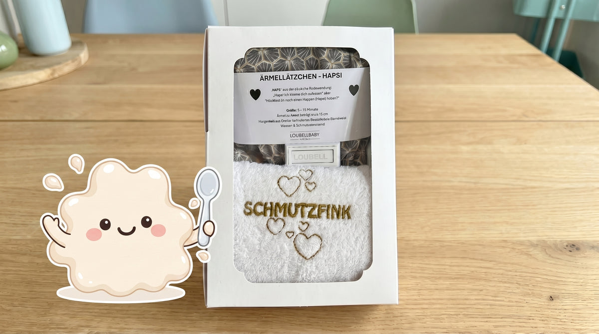 Geschenkbox Grau mit Waschtuch, daneben Klecksi
