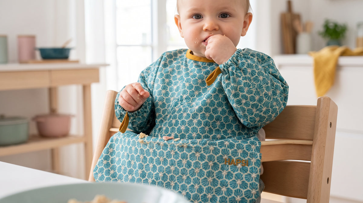 Baby mit türkisem HAPSI Ärmellätzchen isst am Hochstuhl
