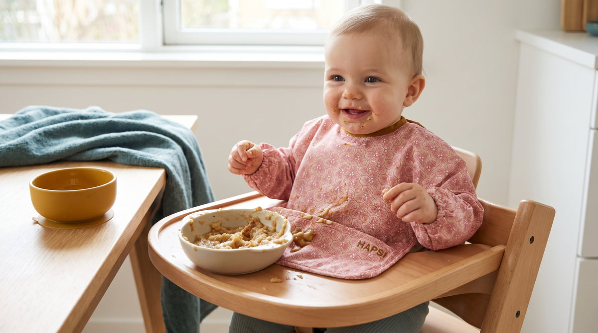 Lachendes Baby mit rosa HAPSI im Hochstuhl