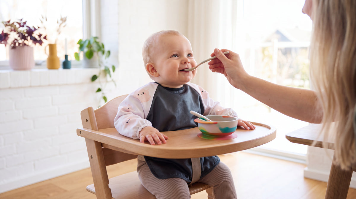 Lachendes Baby mit HAPSI Anthrazit im Hochstuhl wird gefüttert