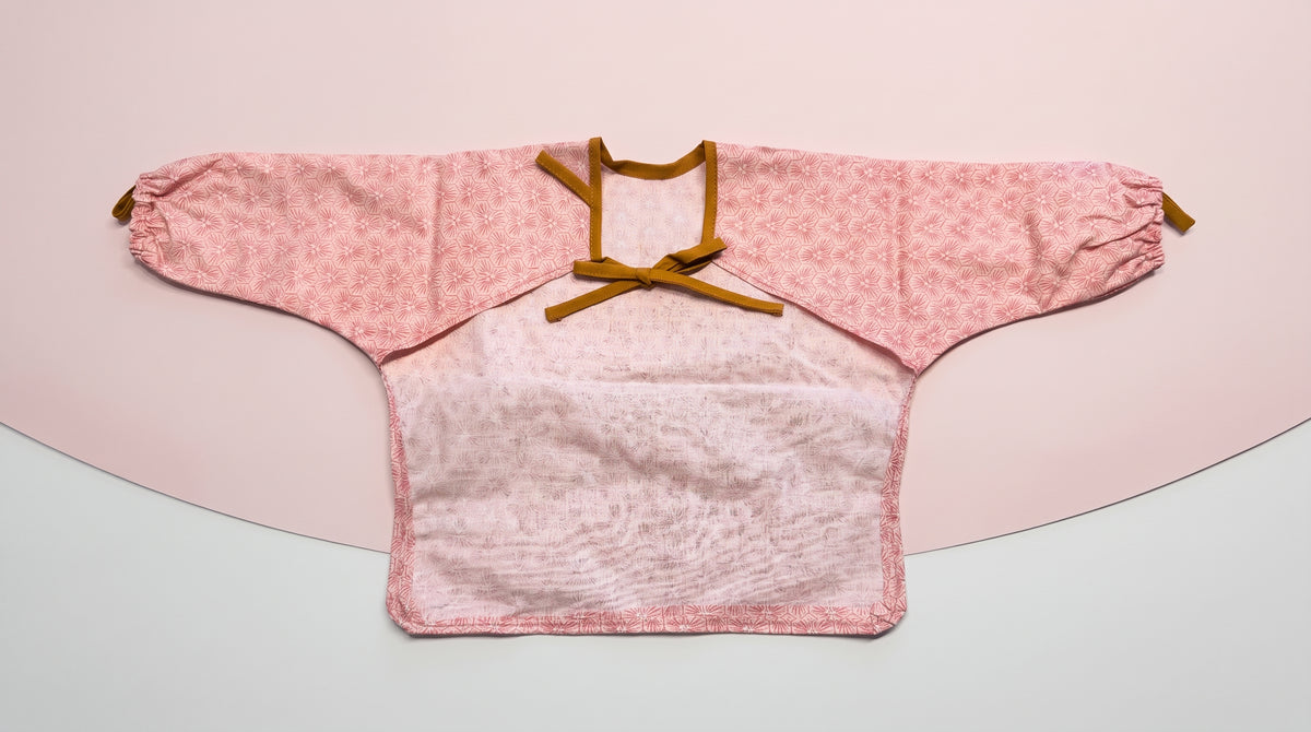 Rückseite des rosa HAPSI Ärmellätzchens mit Bindebändern und Auffangtasche