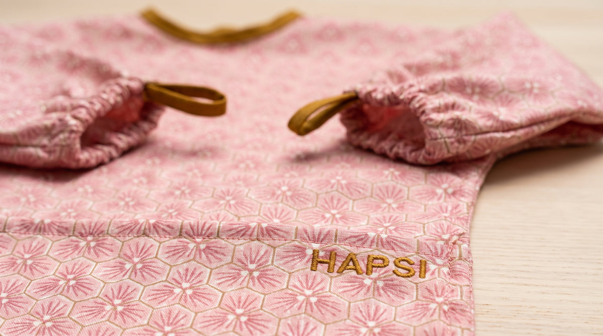 Detail: HAPSI-Logo und Ärmelbündchen mit Laschen am rosa Ärmellätzchen