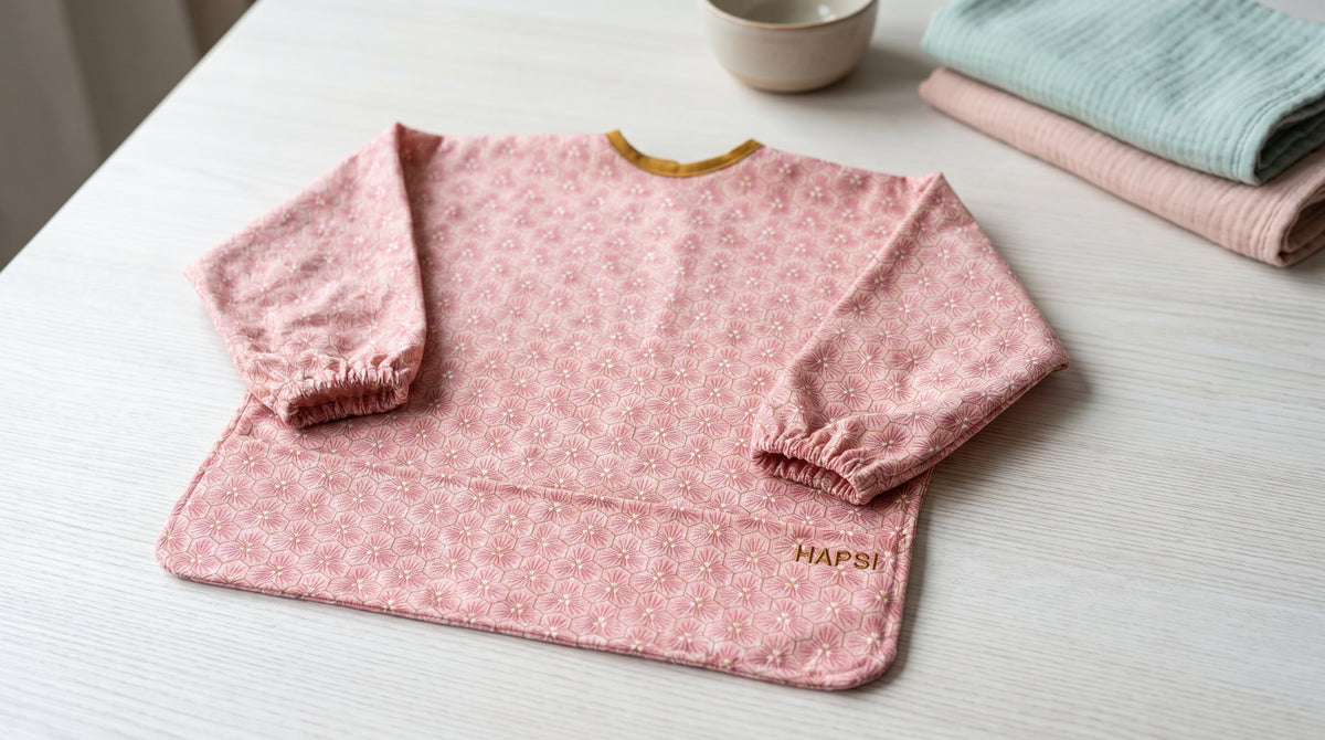 Rosa HAPSI Ärmellätzchen neben einem Waschtuch auf dem Tisch